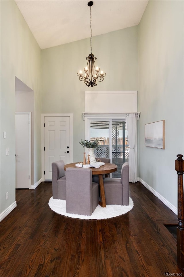 dining room with a chandelier, a towering ceiling, and wood finished floors