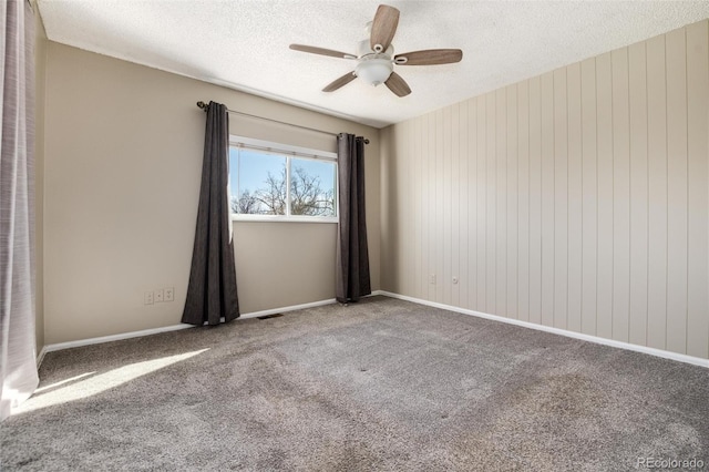 carpeted spare room with visible vents, baseboards, a textured ceiling, and ceiling fan