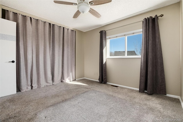 carpeted empty room with visible vents, baseboards, a textured ceiling, and ceiling fan