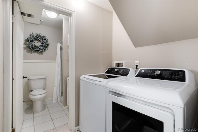 clothes washing area with light tile patterned floors, a wainscoted wall, visible vents, laundry area, and washing machine and dryer