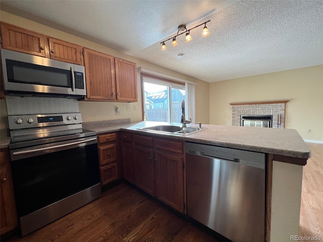 kitchen with stainless steel appliances, sink, dark wood-type flooring, and kitchen peninsula