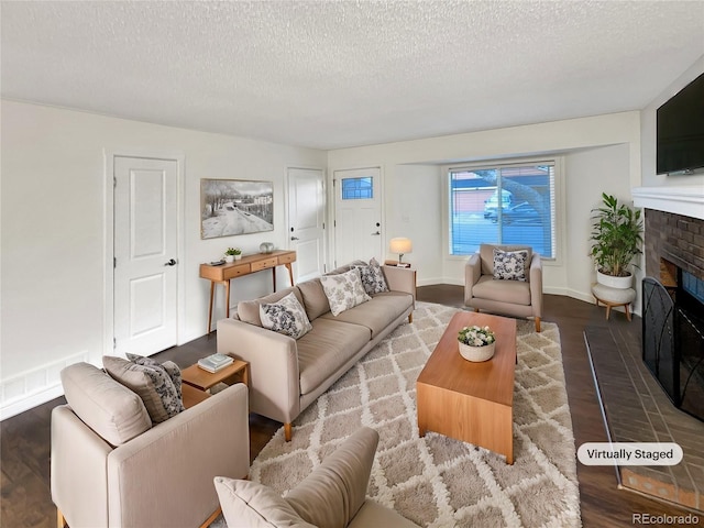 living room featuring hardwood / wood-style floors, a textured ceiling, and a brick fireplace