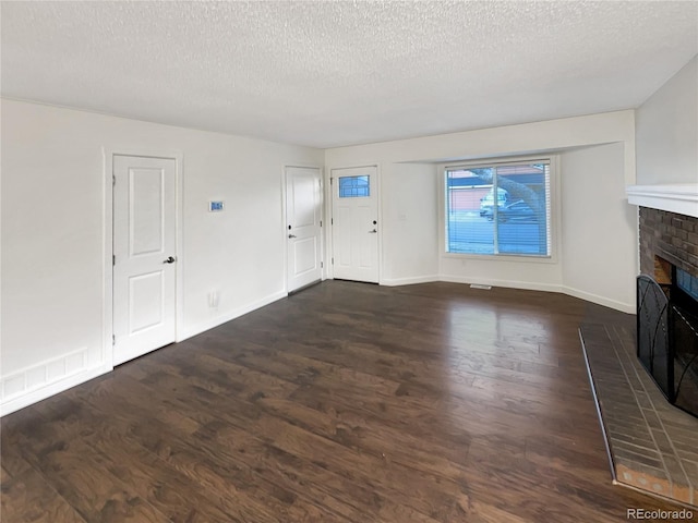 unfurnished living room with a fireplace, dark wood-type flooring, and a textured ceiling