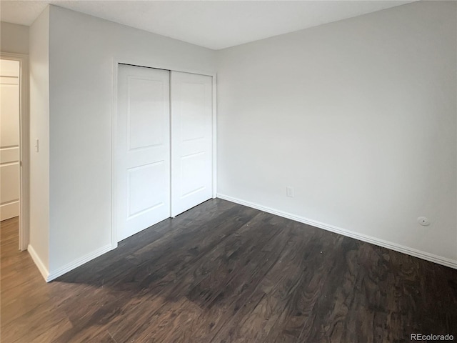 unfurnished bedroom with a closet and dark wood-type flooring