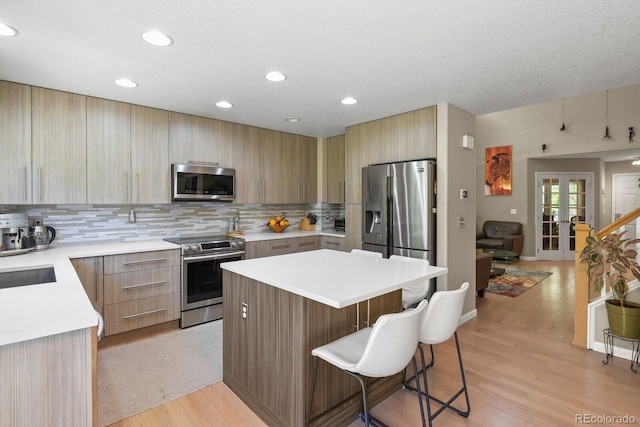 17332 E Lake Ln, Aurora, CO 80016 - kitchen with appliances with stainless steel finishes, a center island, a kitchen bar, modern cabinets, and light countertops