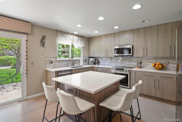 17332 E Lake Ln, Aurora, CO 80016 - kitchen featuring appliances with stainless steel finishes, a breakfast bar area, backsplash, recessed lighting, and light wood-style floors