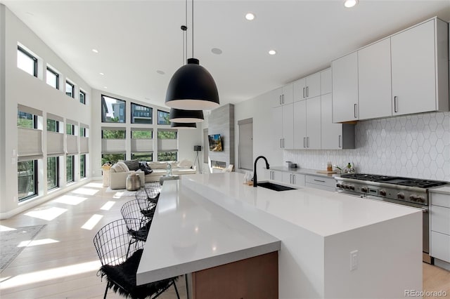 kitchen featuring a kitchen island with sink, sink, hanging light fixtures, tasteful backsplash, and a kitchen bar