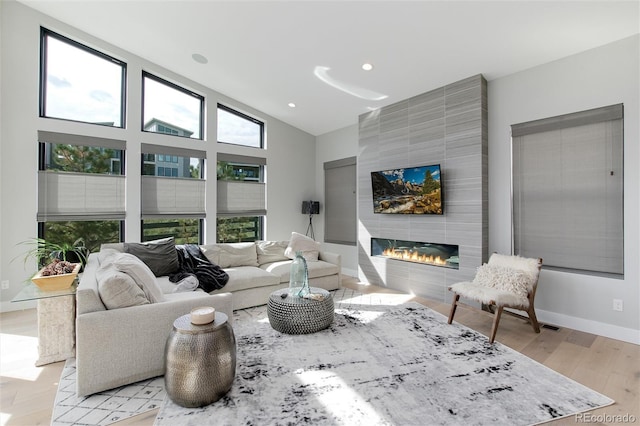 living room featuring a large fireplace, vaulted ceiling, and light wood-type flooring