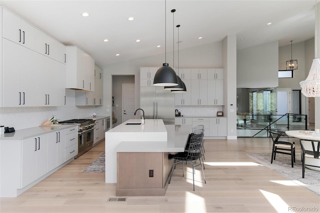 kitchen featuring an island with sink, light wood-type flooring, high end appliances, and a sink