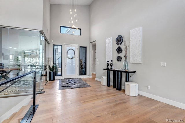 foyer featuring a towering ceiling, baseboards, and wood finished floors