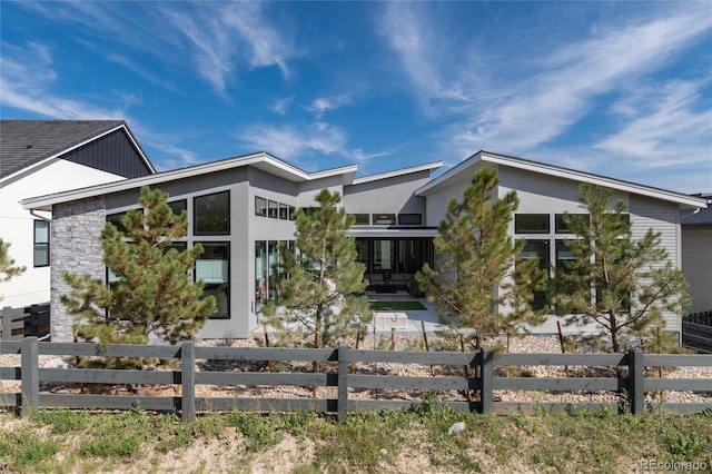 view of front of property with stone siding, a fenced front yard, and stucco siding