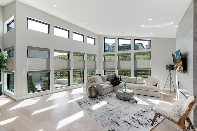 living area with recessed lighting, a healthy amount of sunlight, a high ceiling, and wood finished floors