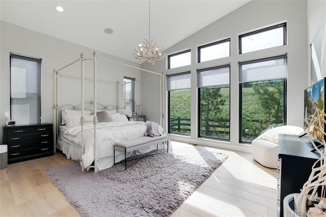 bedroom with light wood-style floors, multiple windows, high vaulted ceiling, and a chandelier