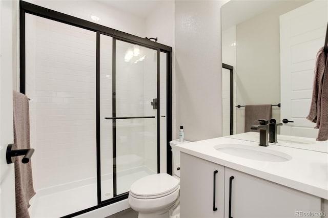 full bathroom featuring vanity, a shower stall, and toilet