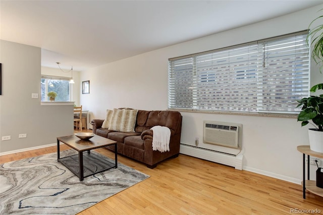 living room featuring a wall mounted air conditioner, light hardwood / wood-style floors, baseboard heating, and a notable chandelier