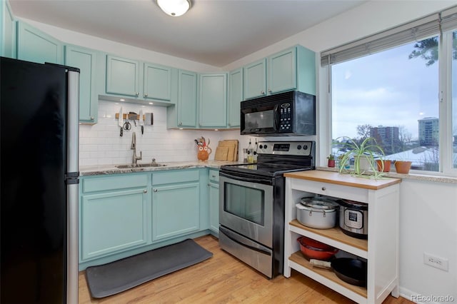 kitchen featuring a healthy amount of sunlight, sink, black appliances, and light wood-type flooring