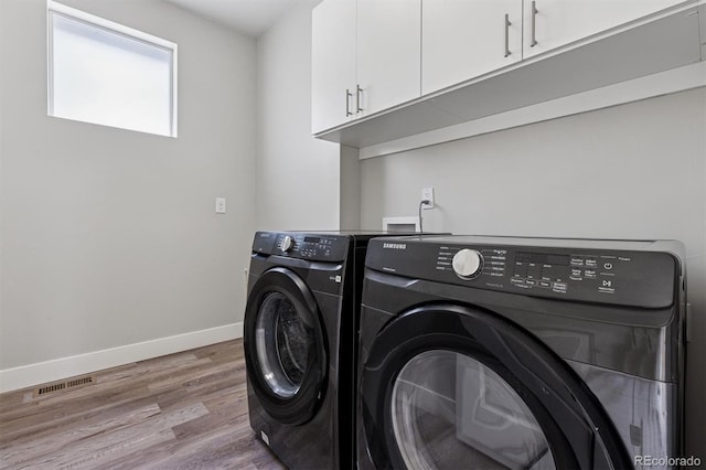 laundry room featuring visible vents, baseboards, wood finished floors, cabinet space, and washer and clothes dryer