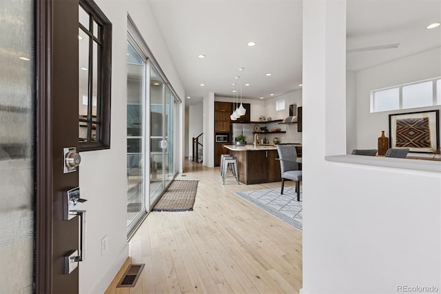 corridor featuring a sink, visible vents, recessed lighting, and light wood finished floors