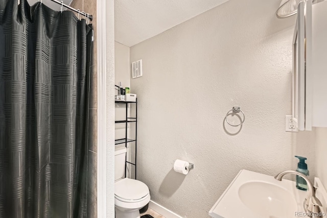 bathroom featuring a shower with curtain, sink, a textured ceiling, and toilet