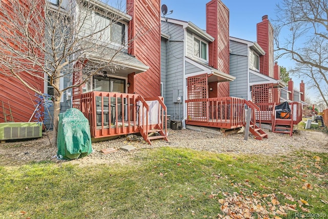 rear view of house with central AC unit and a lawn