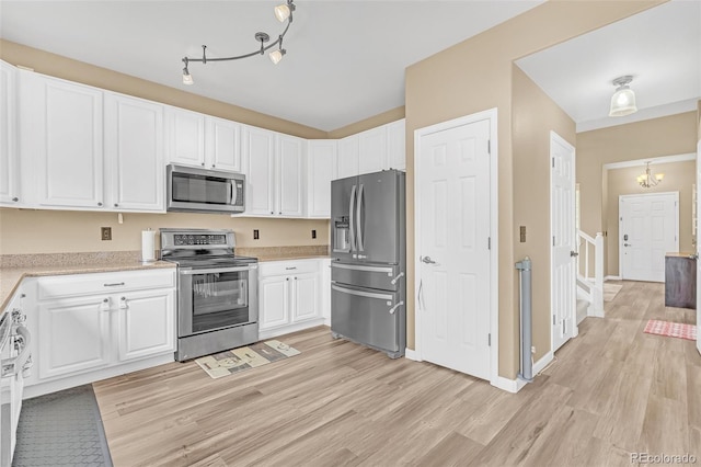 19463 E Hollow Creek Dr, Parker, CO 80134 - kitchen with appliances with stainless steel finishes, a chandelier, light wood finished floors, and white cabinets