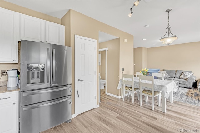 19463 E Hollow Creek Dr, Parker, CO 80134 - kitchen with stainless steel fridge, light wood-type flooring, white cabinets, and open floor plan