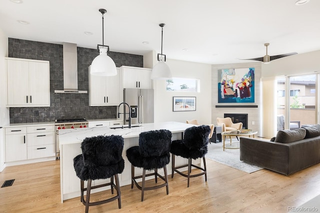 766 Dreamcatcher Ln, Evergreen, CO 80439 - kitchen with high quality appliances, wall chimney range hood, open floor plan, a center island with sink, and backsplash