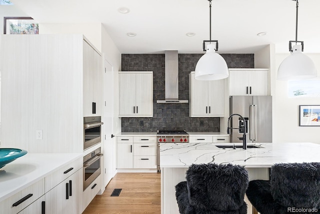 766 Dreamcatcher Ln, Evergreen, CO 80439 - kitchen with wall chimney exhaust hood, stainless steel appliances, pendant lighting, backsplash, and white cabinets