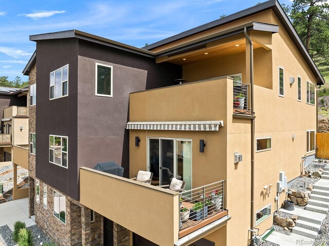 766 Dreamcatcher Ln, Evergreen, CO 80439 - back of house featuring a balcony, stucco siding, and stone siding