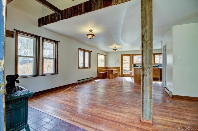 unfurnished living room with decorative columns, hardwood / wood-style floors, and baseboard heating