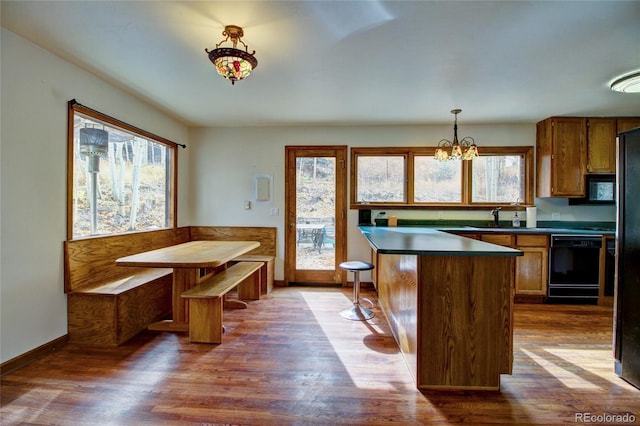 kitchen with dark wood-type flooring, a kitchen island, black appliances, and plenty of natural light