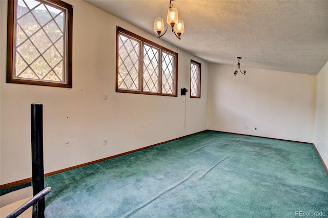 carpeted spare room with a notable chandelier, a textured ceiling, and vaulted ceiling