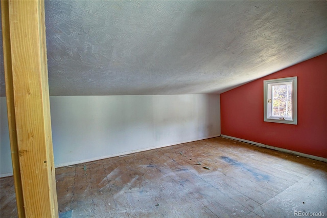 additional living space featuring a textured ceiling and vaulted ceiling