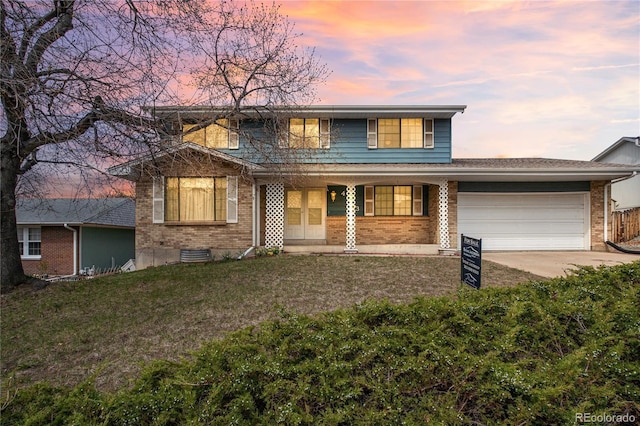 traditional-style home with concrete driveway, a yard, brick siding, and an attached garage