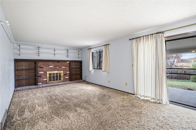 unfurnished living room featuring plenty of natural light, carpet, a brick fireplace, and a textured ceiling