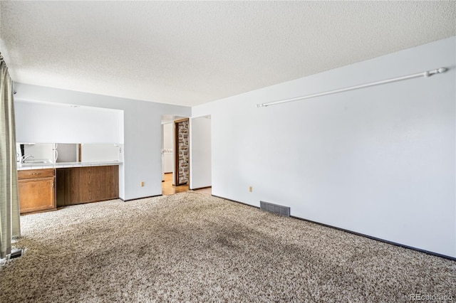unfurnished living room with visible vents, baseboards, carpet, and a textured ceiling