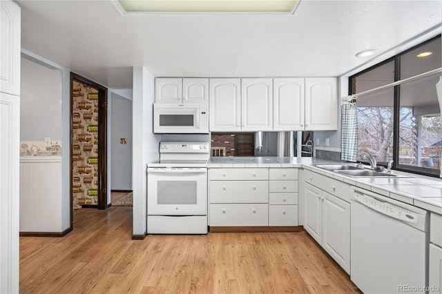 kitchen with white cabinetry, tile countertops, a sink, and white appliances