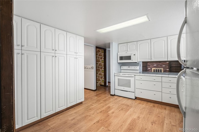 kitchen featuring light wood-style flooring, tile counters, white appliances, and white cabinets