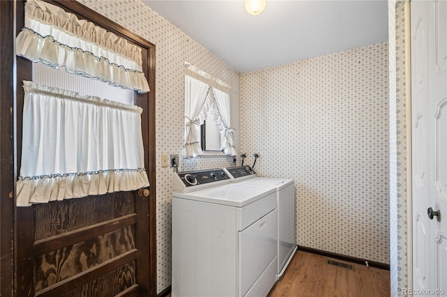 laundry room featuring wallpapered walls, light wood-style flooring, visible vents, washer and clothes dryer, and laundry area