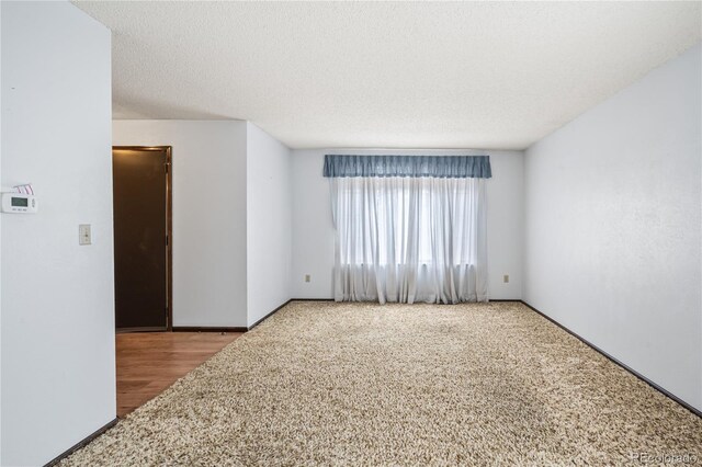 carpeted spare room featuring baseboards and a textured ceiling