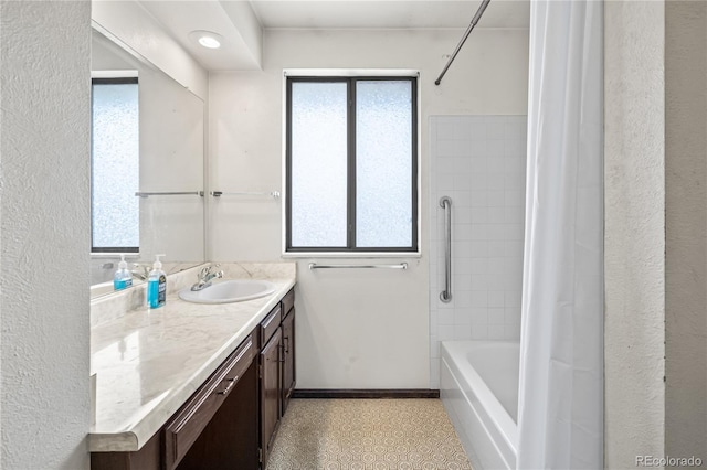 full bath with shower / bath combo, vanity, baseboards, and plenty of natural light