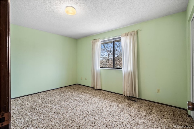unfurnished room with a textured ceiling, baseboards, visible vents, and carpet floors
