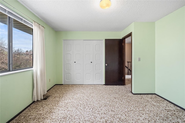 unfurnished bedroom featuring a closet, a textured ceiling, and baseboards