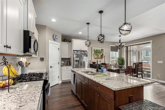 kitchen with white cabinets, hanging light fixtures, an island with sink, and stainless steel appliances