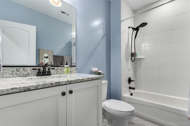 full bathroom featuring vanity, tiled shower / bath combo, and toilet