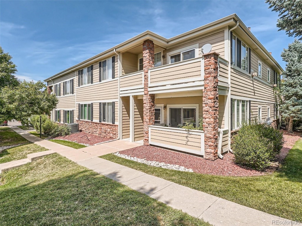 view of front of house featuring cooling unit, a balcony, and a front yard