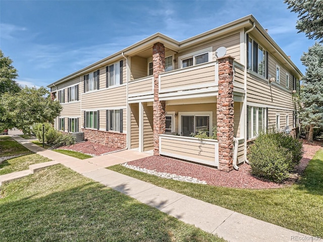 view of front of house featuring cooling unit, a balcony, and a front yard