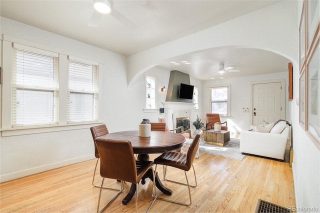 dining room with arched walkways, visible vents, light wood-style flooring, and ceiling fan