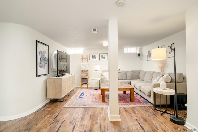 living room featuring light wood-type flooring, plenty of natural light, and baseboards