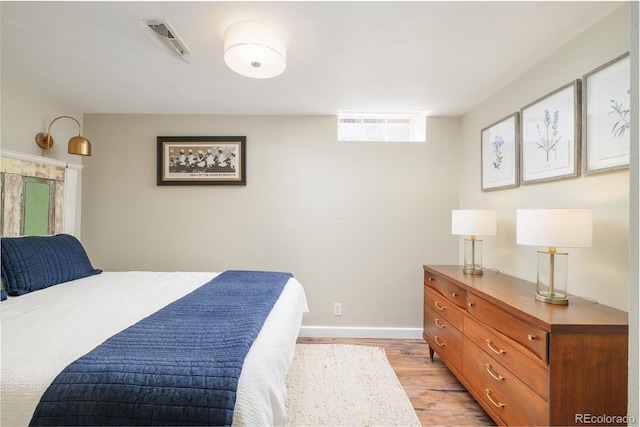 bedroom featuring visible vents, light wood-type flooring, and baseboards